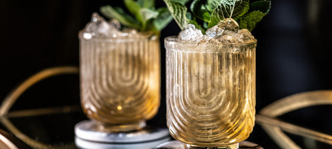 Moody Art Deco lowball glass with a whiskey cocktail in speakeasy lighting