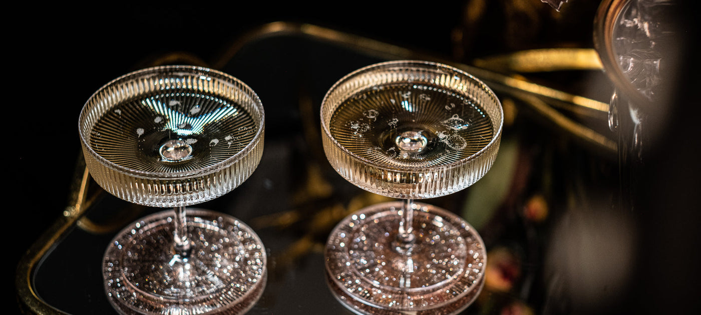 Two ribbed Art Deco crystal coupes on a black mirrored tray with gold trim