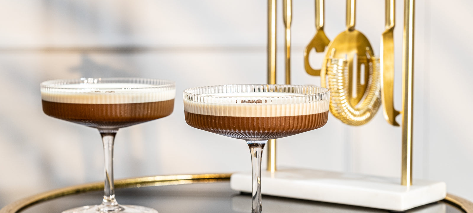 Art Deco crystal coupe cocktails styled with gold bar tools