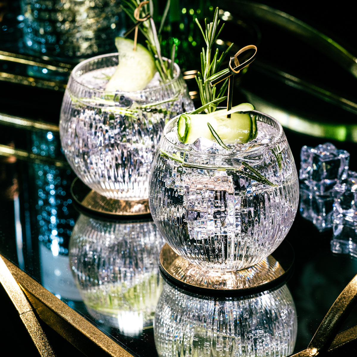 Copa de Balon gin and tonic glasses with cucumber and rosemary on a mirrored gold tray